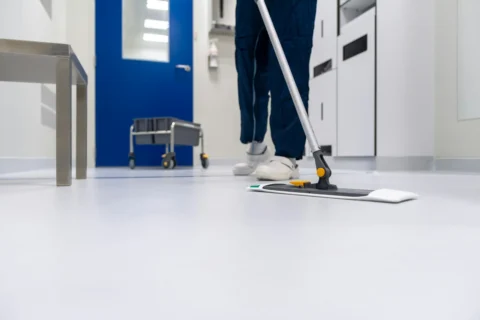 Cleaner in hazmat suit mopping a floor with care.