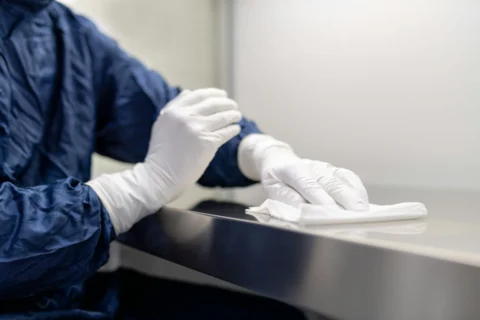 Professional in hazmat suit cleaning a surface with a microfiber cloth.